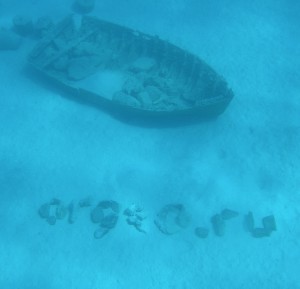 Надпись камнями на дне рифа Хургады рядом с затонувшей лодкой